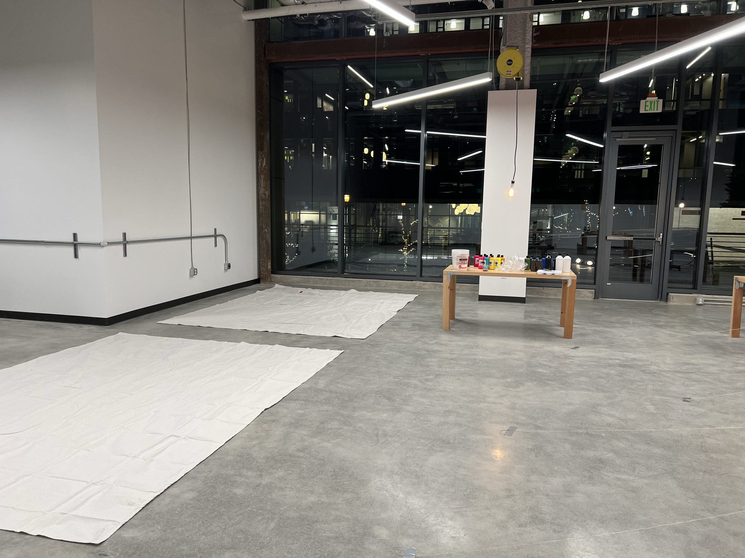 The empty Ground Floor Studio before installation — concrete floor, glass curtain wall, columns.