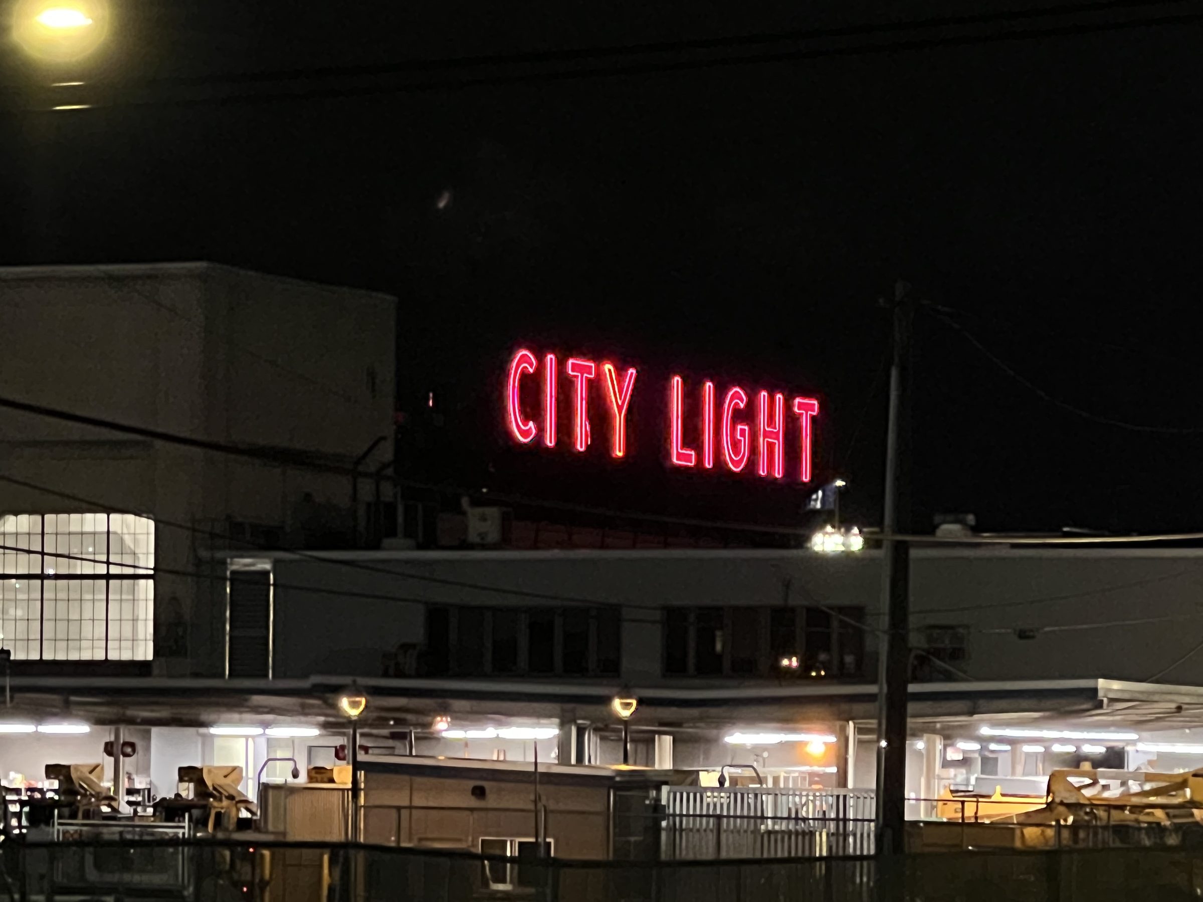 The CITY LIGHT neon atop its working storefront in Georgetown, depot bays lit below.
