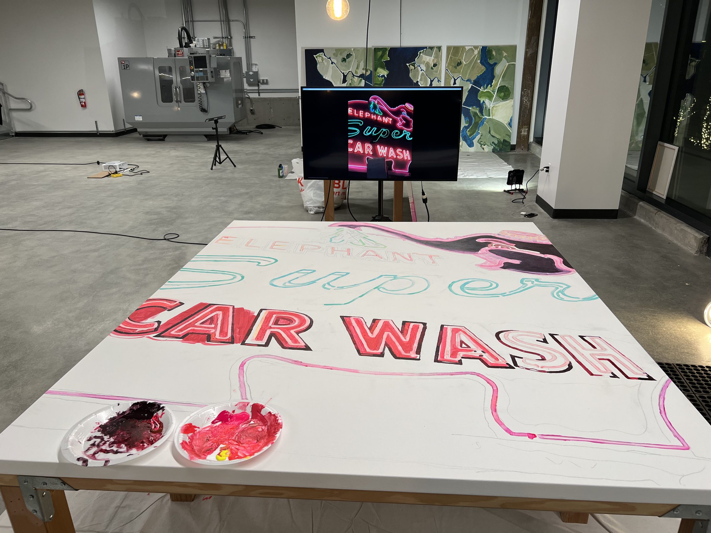 The CAR WASH panel mid-process from above; brush, paper plate of pink, the lettering crystallising.