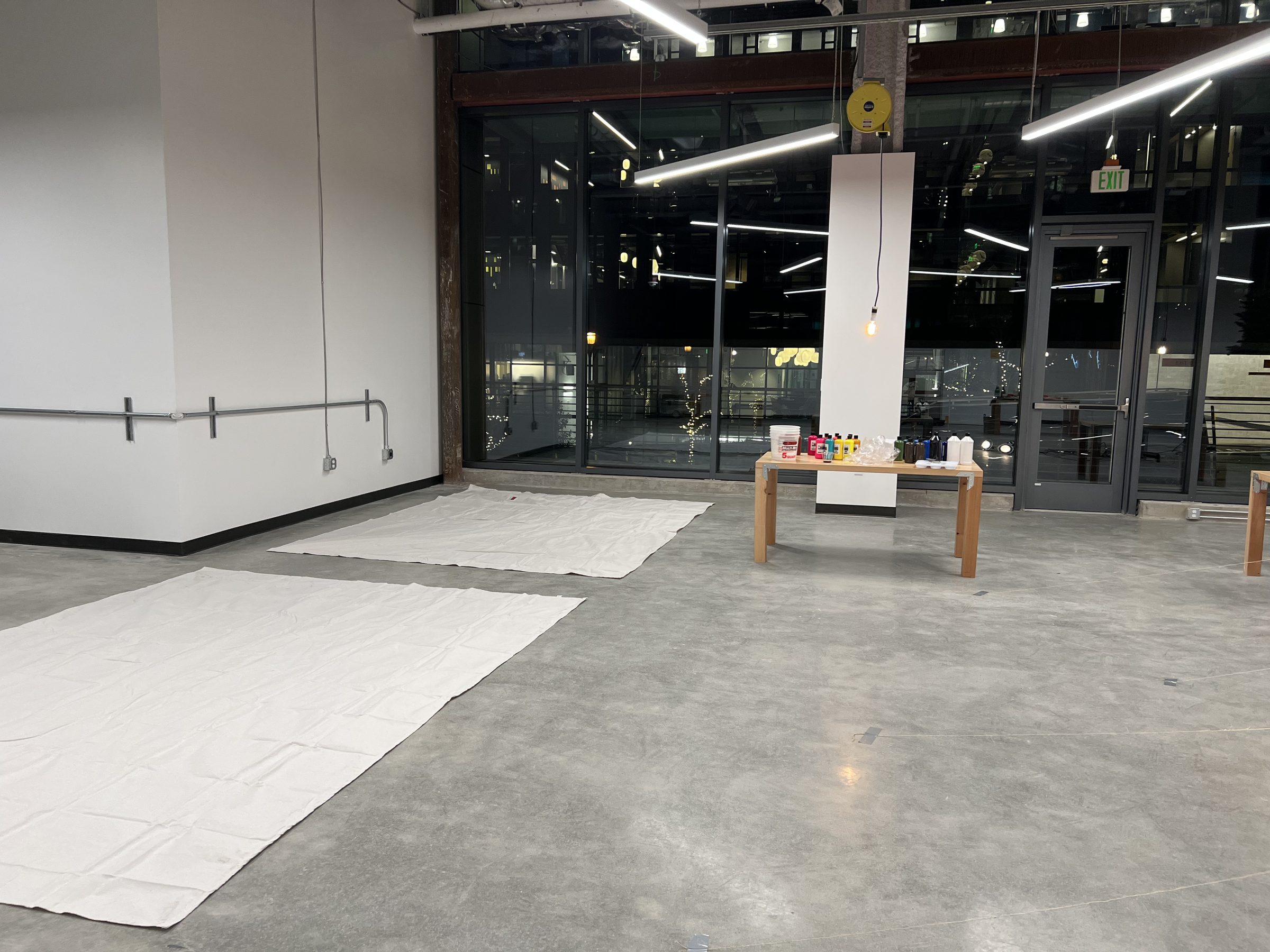 The empty Ground Floor Studio before the work — concrete floor, glass curtain wall, columns.
