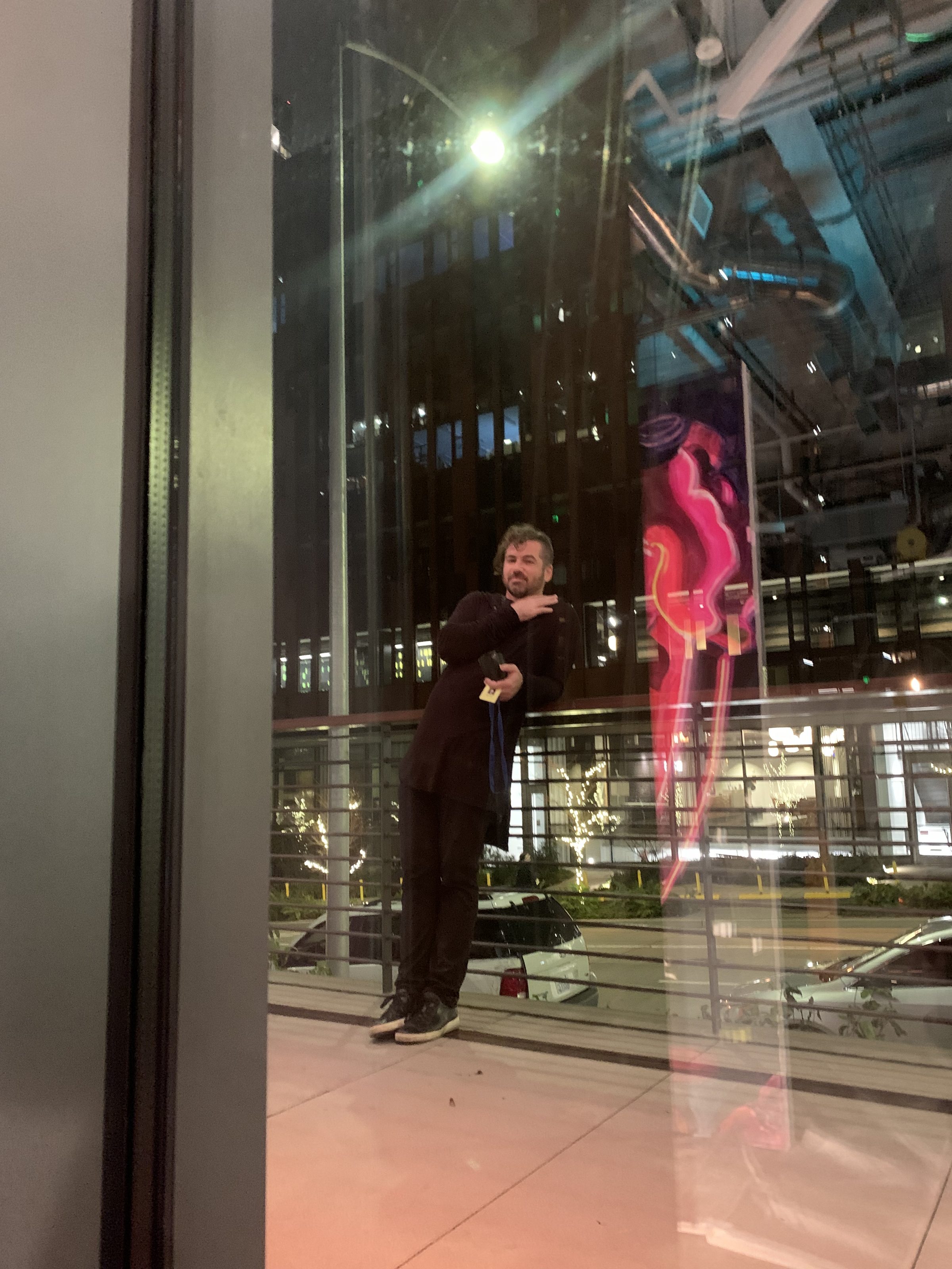 Joshua Borsman at the City Light opening, the gallery glowing behind the glass.