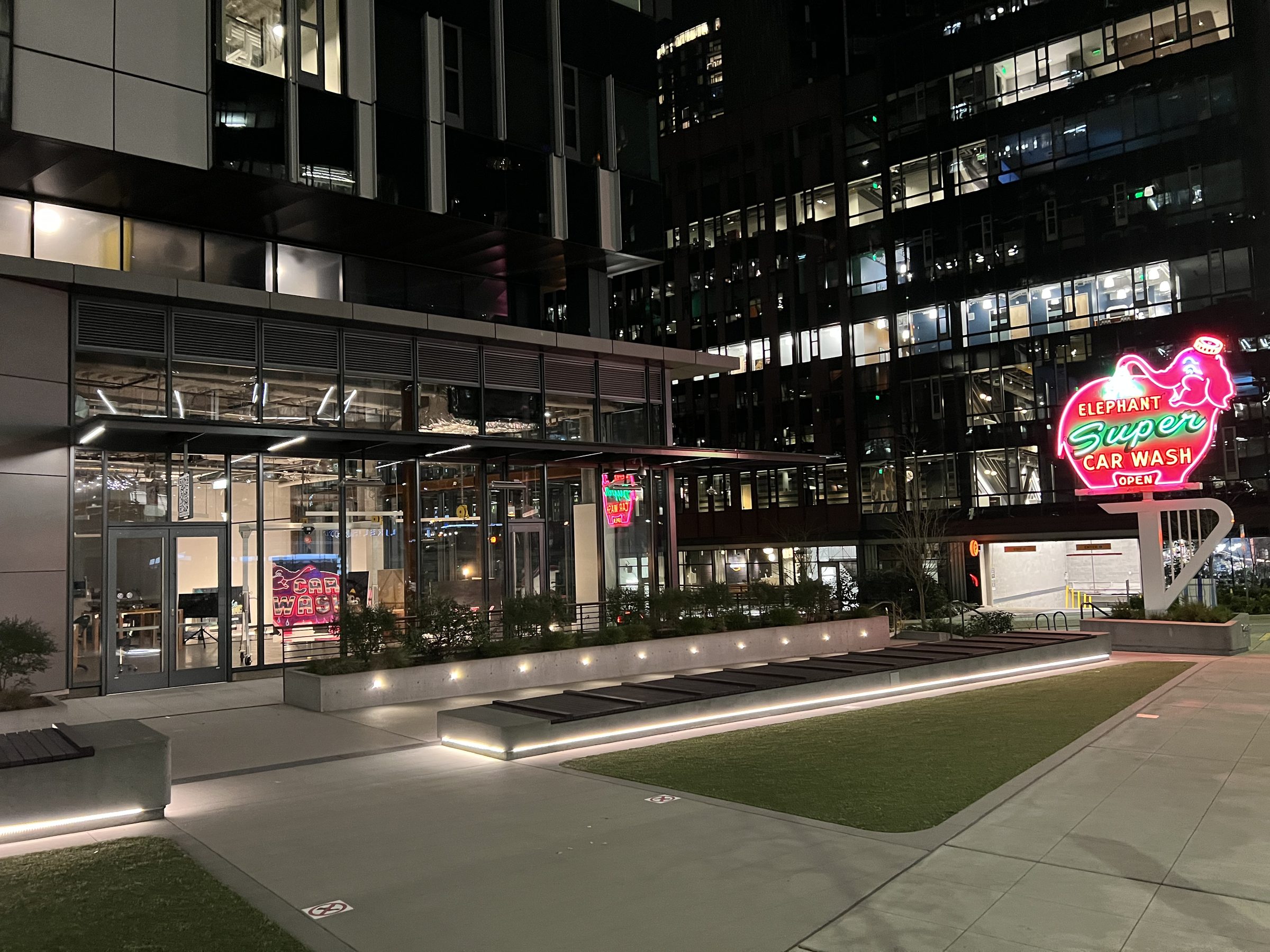 Opening night exterior view — the lit gallery glowing pink and red into the night.